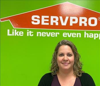 Kelli, office manager, pictured in front of SERVPRO logo