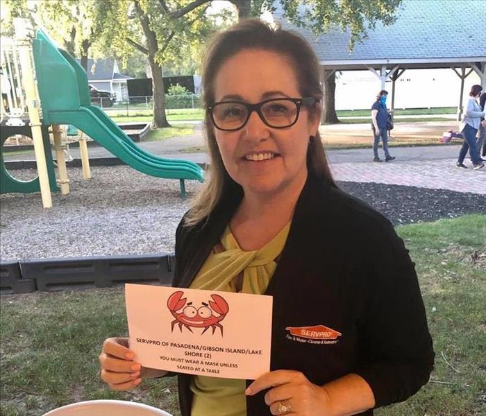 Woman holding crab feast sign for SERVPRO