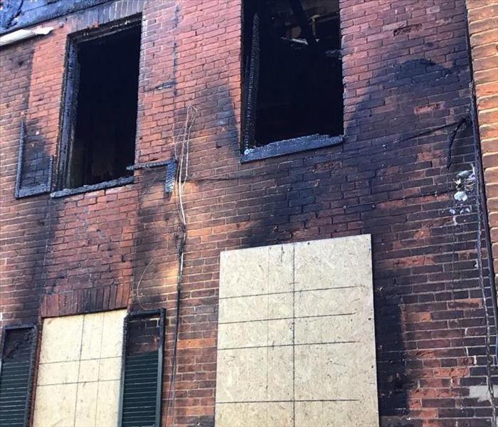 brick building with fire damage and board over windows